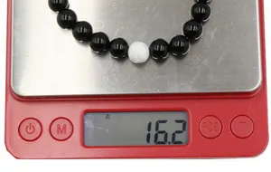 Weight display of an 8mm black onyx and white turquoise beaded bracelet showing 16.2g