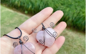 Detail of wire-wrapped rose quartz heart pendant with intricate handmade spiral wire design