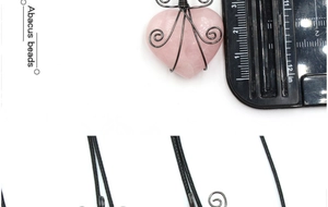 Detail of pink crystal heart pendant with black wire wrap craftsmanship and size scale