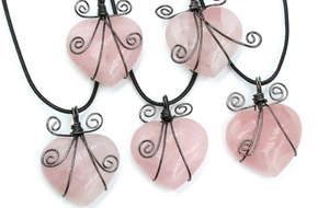 Detail of rose quartz heart pendants with handmade black wire wrapping and scroll design