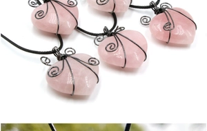 Detailed view of pink rose quartz heart pendants with black wire wrapping and woven cords