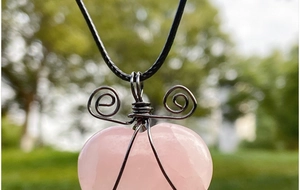 Detail of handmade wire-wrapped heart-shaped pink crystal pendant with black cord necklace