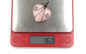 Detail of handmade heart-shaped rose quartz pendant with dark wire wrap on 16.0g scale