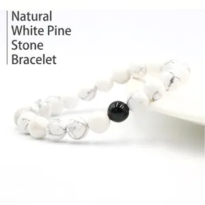 Natural white turquoise bead bracelet with single black marble accent on a white ceramic plate