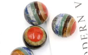 Macro view of polished 20mm chakra crystal spheres with multi-layered gemstone stripes