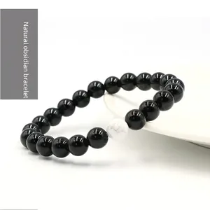 Natural 8mm black obsidian beaded bracelet with white turquoise bead on white ceramic plate