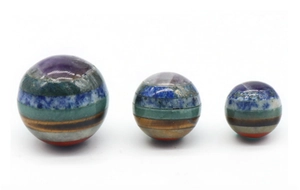 Detailed view of three polished 20mm chakra gemstone spheres with layered natural stones