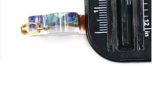 Macro side view of round resin pendant showing multi-color crystals and 0.5-inch thickness