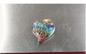 Macro view of chakra heart pendant featuring natural colorful stones and copper spiral wire