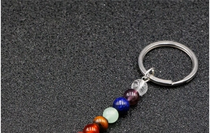 Detail of a seven chakra gemstone keychain with silver metal ring on black surface