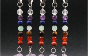 Detailed view of 7 chakra natural gemstone bead pendants with amethyst raw crystal