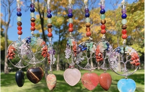 Outdoor view of seven colorful life tree crystal pendants with heart-shaped gemstones