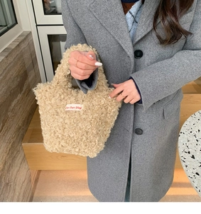 Detailed macro of beige plush teddy fleece texture and woven logo on mini handbag
