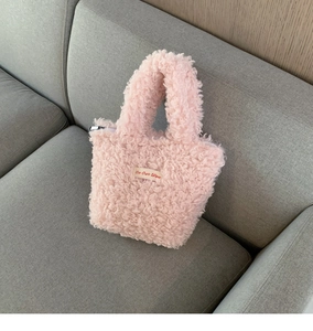 Close-up of pink faux shearling mini tote bag featuring On Our Way fabric patch