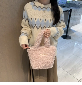 Detailed view of pink plush handbag with soft faux shearling texture and top handles