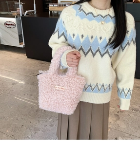 Detailed shot of a pink plush handbag featuring On Our Way label and soft teddy texture