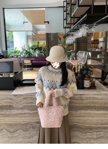 Close-up of pink fluffy plush handbag with textured wool material in a cozy cafe setting