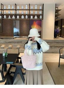 Detail of pink plush handbag with On Our Way label in a modern cafe setting