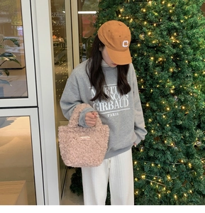 Close-up of pink faux shearling mini tote bag paired with grey autumn casual sweatshirt