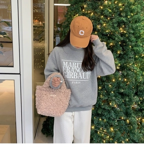 Pink plush mini handbag styled with a grey sweatshirt and festive holiday background