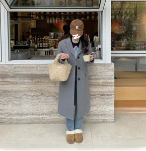 Close-up of a cozy beige sherpa fleece mini handbag paired with a stylish grey coat
