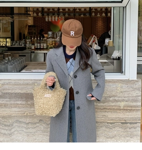 Detail of beige faux fur mini tote bag styled with a wool coat and baseball cap