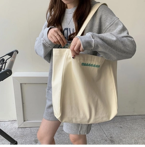 Close-up of off-white canvas tote bag with green embroidered maaaaaas letters