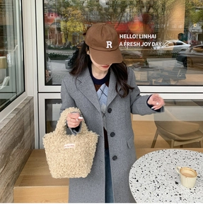 Detail showing plush beige shearling handbag with embroidery tag for winter street style