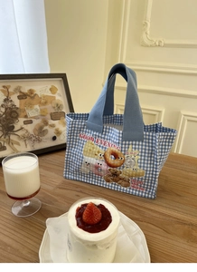 Dettaglio della borsa bento in tela a quadretti blu con orsetto e illustrazioni di ciambelle
