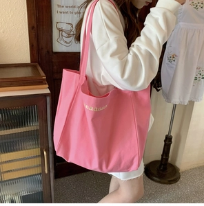 Close-up of pink canvas tote bag with letter embroidery and durable shoulder strap