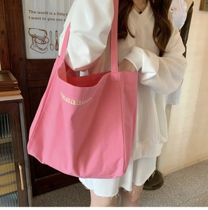 Detail of pink canvas tote bag showing wide shoulder strap and haaaaaa embroidery