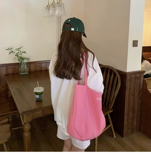 Pink canvas tote bag on a wooden cafe chair with soft indoor lighting