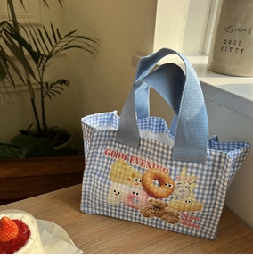 Dettaglio della borsa porta pranzo a quadri blu con orsetti su tavolo in legno