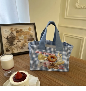 Dettaglio dell'illustrazione con orso e ciambella su borsa da pranzo in tela a quadretti
