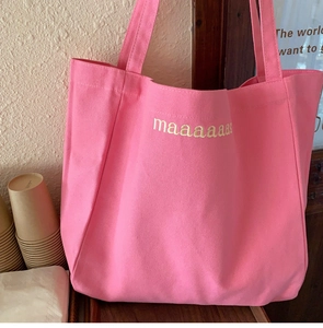 Close-up of bright pink canvas tote bag with yellow maaaaaaas lettering print