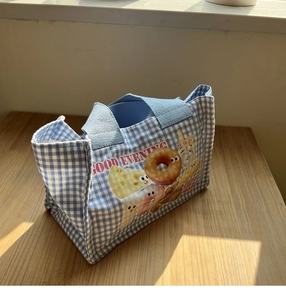 Dettaglio della borsa da pranzo a quadretti blu con illustrazioni di ciambelle e manici