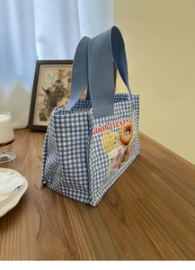Dettaglio ravvicinato della borsa pranzo in tela a quadretti blu con stampa di dolci su legno