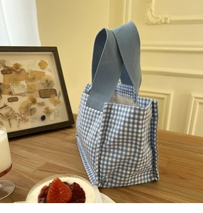 Borsa termica a quadretti bianchi e blu con ampi manici su un tavolo in legno