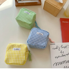 Tre pochette colorate a quadretti vichy con etichetta lime su tavolo bianco