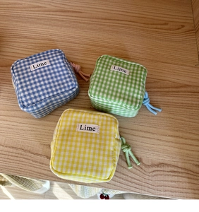 Dettaglio di mini astucci in tela a quadretti blu verdi e gialli con etichette Lime