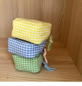 Tre astucci in cotone a quadretti vichy con cerniere in corda su uno scaffale di legno