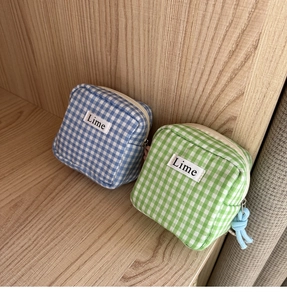 Dettaglio di astucci in cotone a quadretti blu e verdi con etichetta Lime e zip