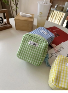 Dettaglio di pochette in tessuto vichy a quadretti verde, blu e giallo con etichetta Lime