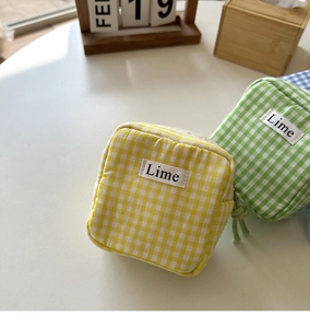 Dettaglio di mini astucci a quadretti gialli e verdi con cerniere e cinturini