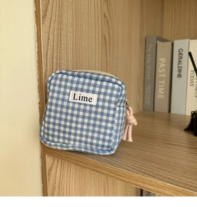 Dettaglio della borsa per assorbenti a quadretti blu con etichetta Lime e nodo rosa