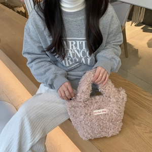 Pink plush faux fur handbag with On Our Way label shown in a casual lifestyle setting