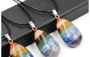 Macro shot of colorful seven chakra teardrop crystal pendants with layered gemstones