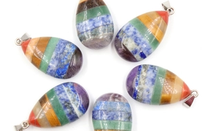 Macro detail of layered teardrop chakra stone pendants with multiple natural gemstones
