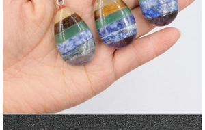 Macro view of seven chakra rainbow stone teardrop pendants held in hand with metal loops