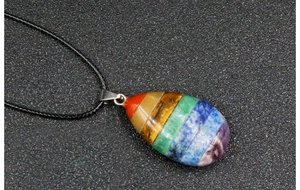 Macro shot of chakra yoga necklace with colorful teardrop gemstone and black cord